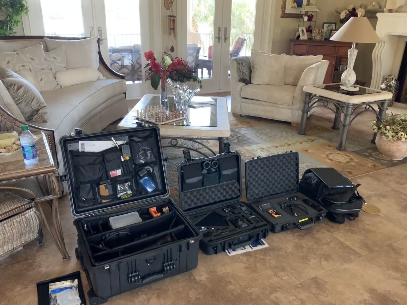 Pelican cases of counter-surveillance equipment open on a residential floor, deployed for an on-site engagement.